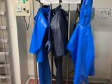 trois imperméables bleus suspendus à un porte-manteau dans une pièce
