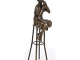 une statue en bronze représentant un homme assis sur un tabouret