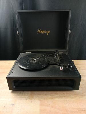 un tourne-disque noir posé sur une table en bois