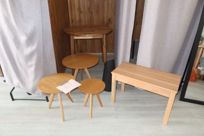 three wooden tables and two stools in a room