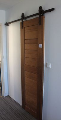 une porte coulissante dans un coin de la pièce, à côté d'un lit