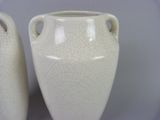 two white vases sitting side by side on a table