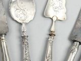 five silverplated spoons and a knife are lined up on a table