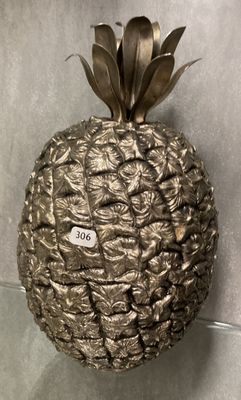 un ananas en métal posé sur une étagère en verre fixée au mur