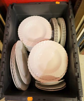 beaucoup d'assiettes dans un récipient en plastique posé par terre