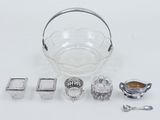 a glass bowl, silverware, and spoons on a white surface