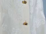 a close up of a white dress with gold buttons