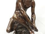 statue en bronze représentant un garçon assis sur un rocher, coiffé d'un chapeau