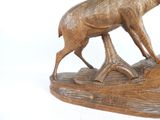 a wooden sculpture of a deer on a rock