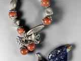 two pieces of silver and coral jewelry on a white surface