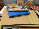 a pile of books on a desk next to a pile of other books