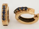 une paire de boucles d'oreilles créoles en or et saphir bleu sur fond blanc