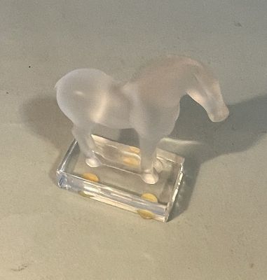 a plastic horse that is standing on a glass block
