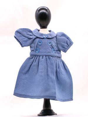 une robe bleue pour une poupée posée sur un socle noir, sur fond blanc