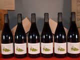 six bottles of red wine are lined up on a table