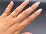 the woman ' s hand is holding a gold ring with a diamond on it