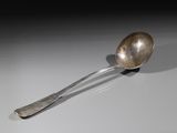 silver spoon sitting on a white surface with a shadow on it