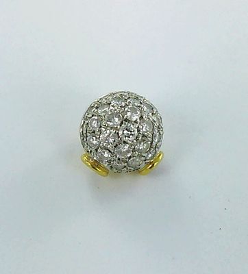 une photo d'une bague avec une boule en diamant posée sur une surface blanche