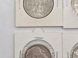four different types of silver coins are in a white box