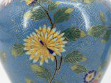 a blue vase with a yellow flower on it