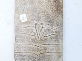 a stone plaque on the wall with a tag on it