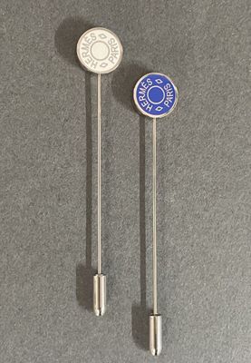 pair of silver and blue lapel pins on a gray surface
