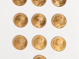 a close up of a number of gold coins on a white surface