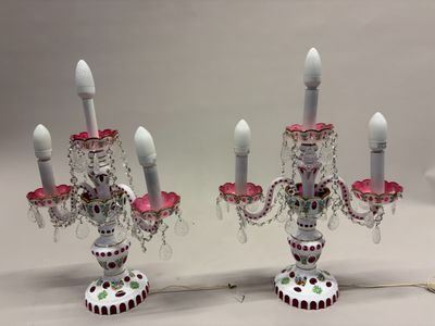 une paire de bougeoirs roses et blancs avec des lustres en cristal