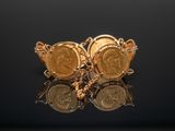 a close up of a pair of gold coin earrings on a black surface