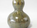 un vase vert posé sur une surface blanche
