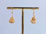 the gold earrings are hanging from a gold stand on a blue background
