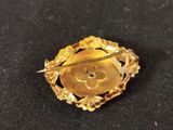 a close up of a gold brooch with a flower on it