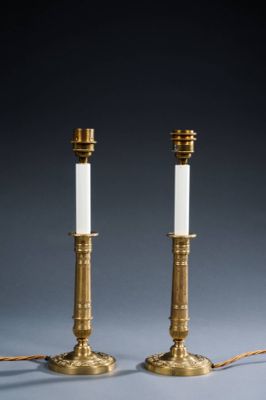 a pair of brass candles with white candlesticks on them