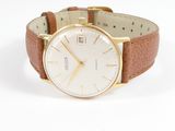 gros plan d'une montre sur une surface blanche avec un bracelet marron