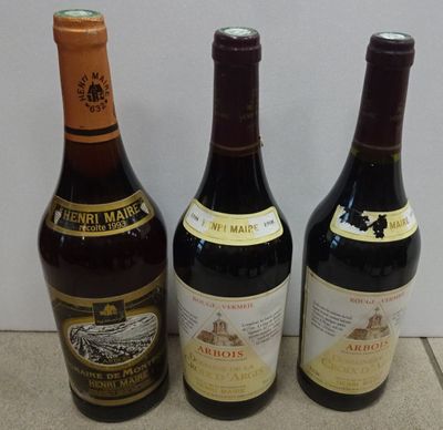 three bottles of wine are lined up on a tile floor