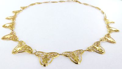 a close up of a gold necklace on a white surface