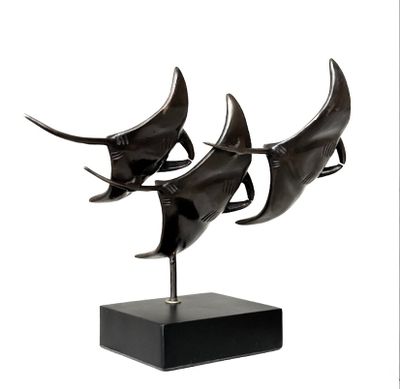 trois sculptures en bronze représentant un requin, posées sur un socle noir