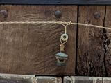 a picture of a wooden door with a bell hanging from it ' s side