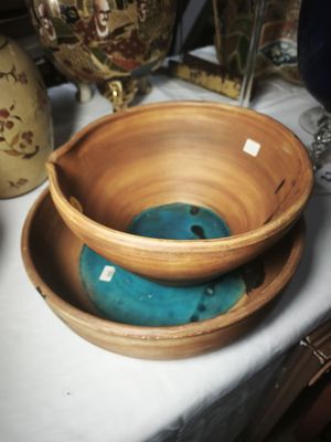 a bowl and a bowl on a table with vases in the background