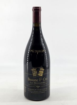 the bottle of red wine is sitting on a white surface