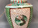 un vase vert et rouge orné d'un oiseau