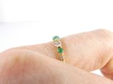 a person ' s hand holding a ring with three emerald stones
