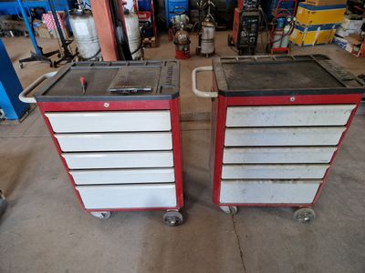 pair of red and white tool boxes with wheels in a garage