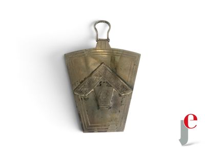 une petite clochette en laiton accrochée à un mur blanc