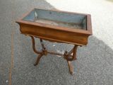 une petite table en bois avec un plateau en verre, posée sur le trottoir