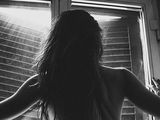 black and white photo of a woman standing in front of a window