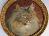 un tableau représentant un chat, dans un cadre doré, accroché au mur