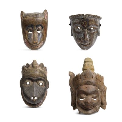 quatre masques en bois de formes et de tailles différentes sur un fond blanc