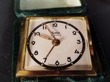 a small square clock sitting on top of a green case
