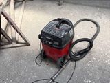 un aspirateur rouge et noir posé par terre dans un garage